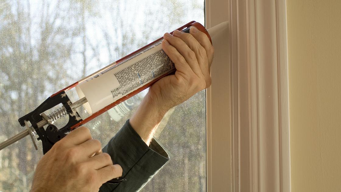 man caulking window during the day